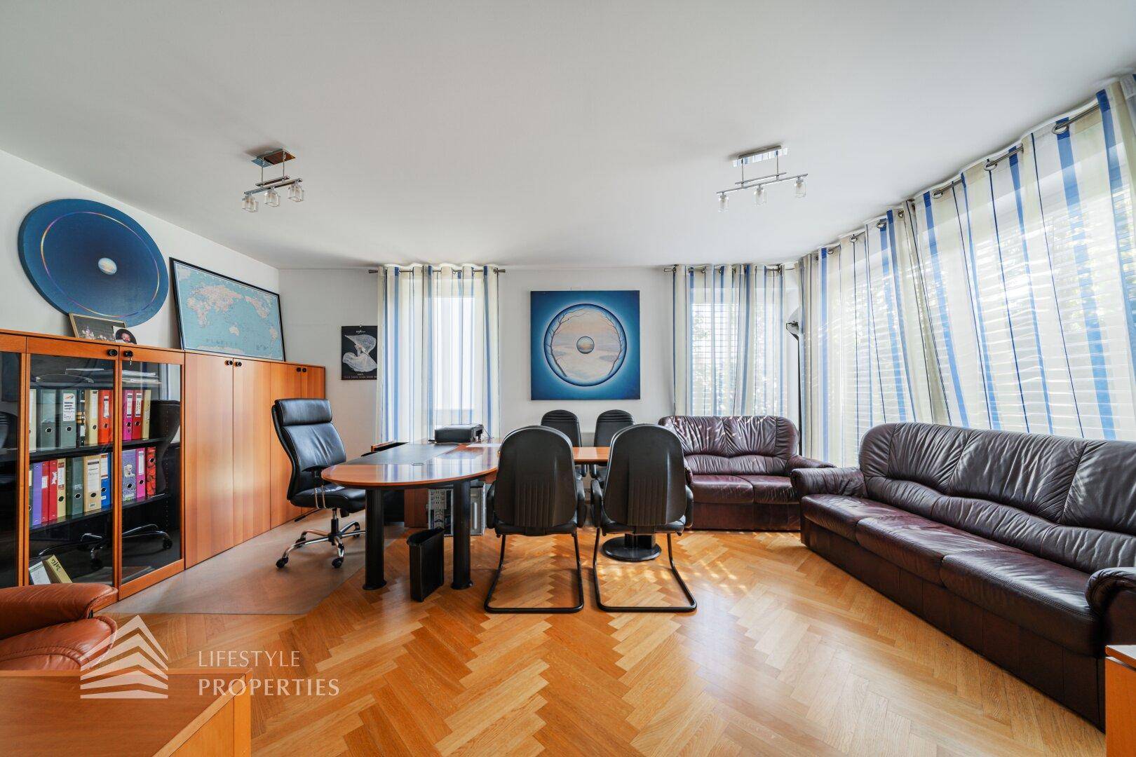 Großes Büro mit Holzparkett, Schreibtisch und bequemen Ledersofas.