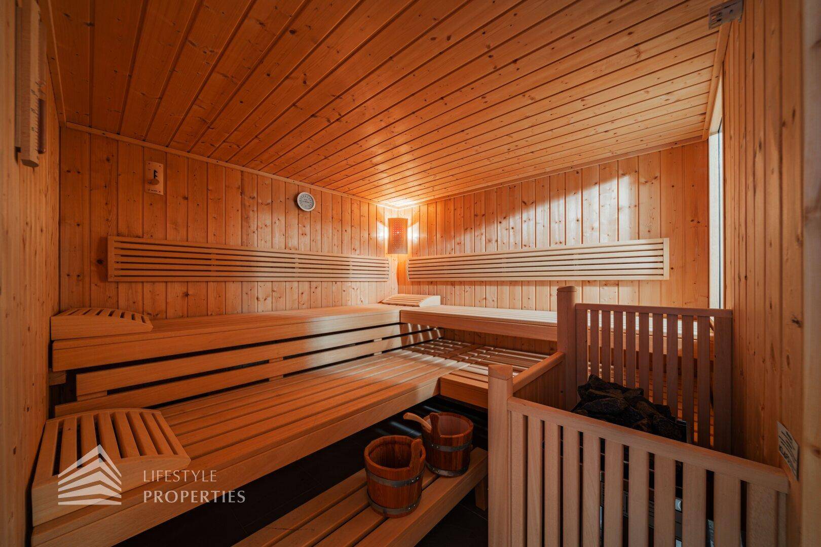 Traditionelle Holzsauna mit mehreren Bänken und klassischem Saunaofen für Entspannung.