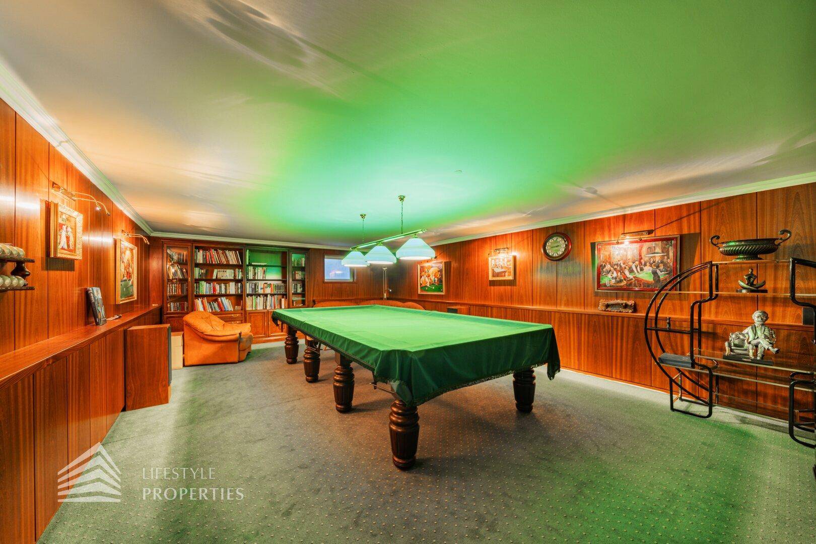 Gemütlicher Spielraum mit Billardtisch, Holzvertäfelung und integrierten Bücherregalen.