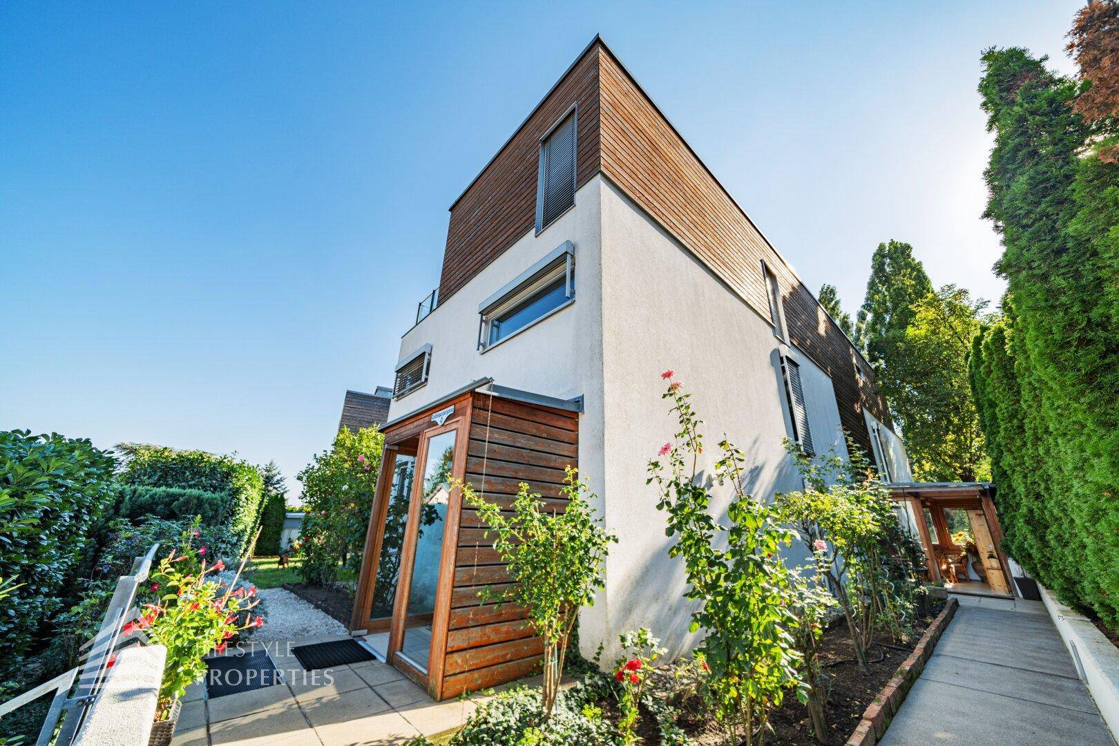 Moderne Architektur des Hauses mit Holzverkleidung und gepflegtem Vorgartenbereich.