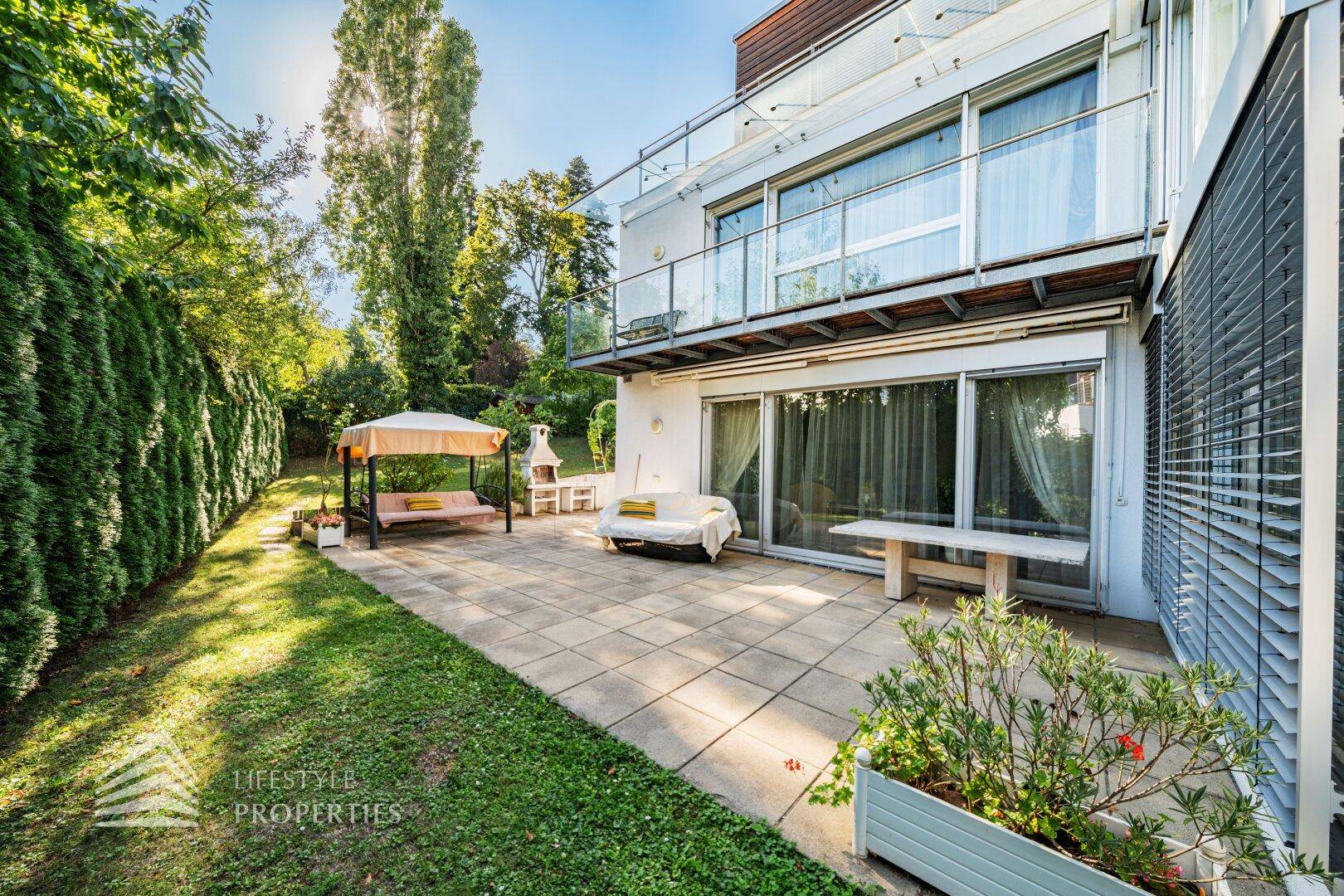 Geräumige Terrasse mit Steinplatten, Gartenmöbeln und direktem Zugang zum Rasen.
