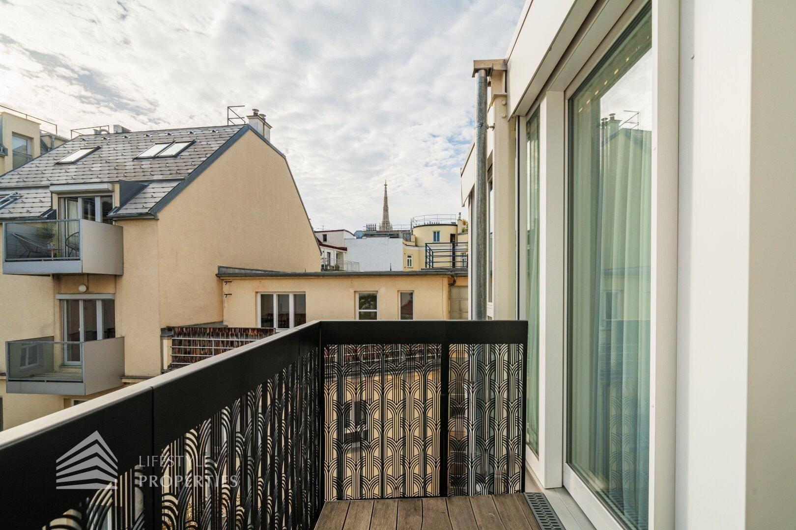 Heller Balkon mit Holzboden und modernem Geländer, bietet einen weiten Blick über die Stadt.
