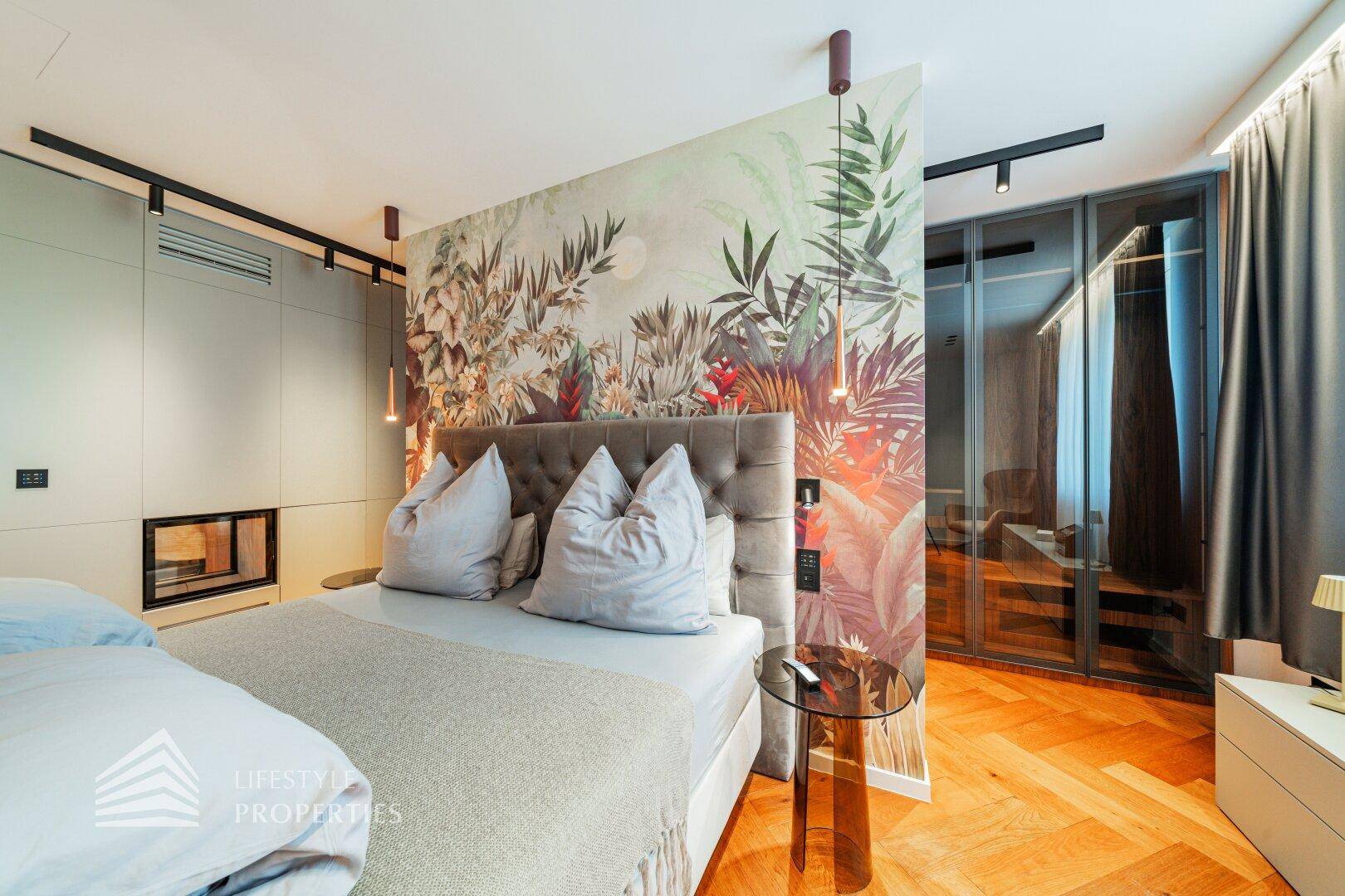 Modernes Schlafzimmer mit floraler Tapete, großem Bett, begehbarem Kleiderschrank und Kamin.