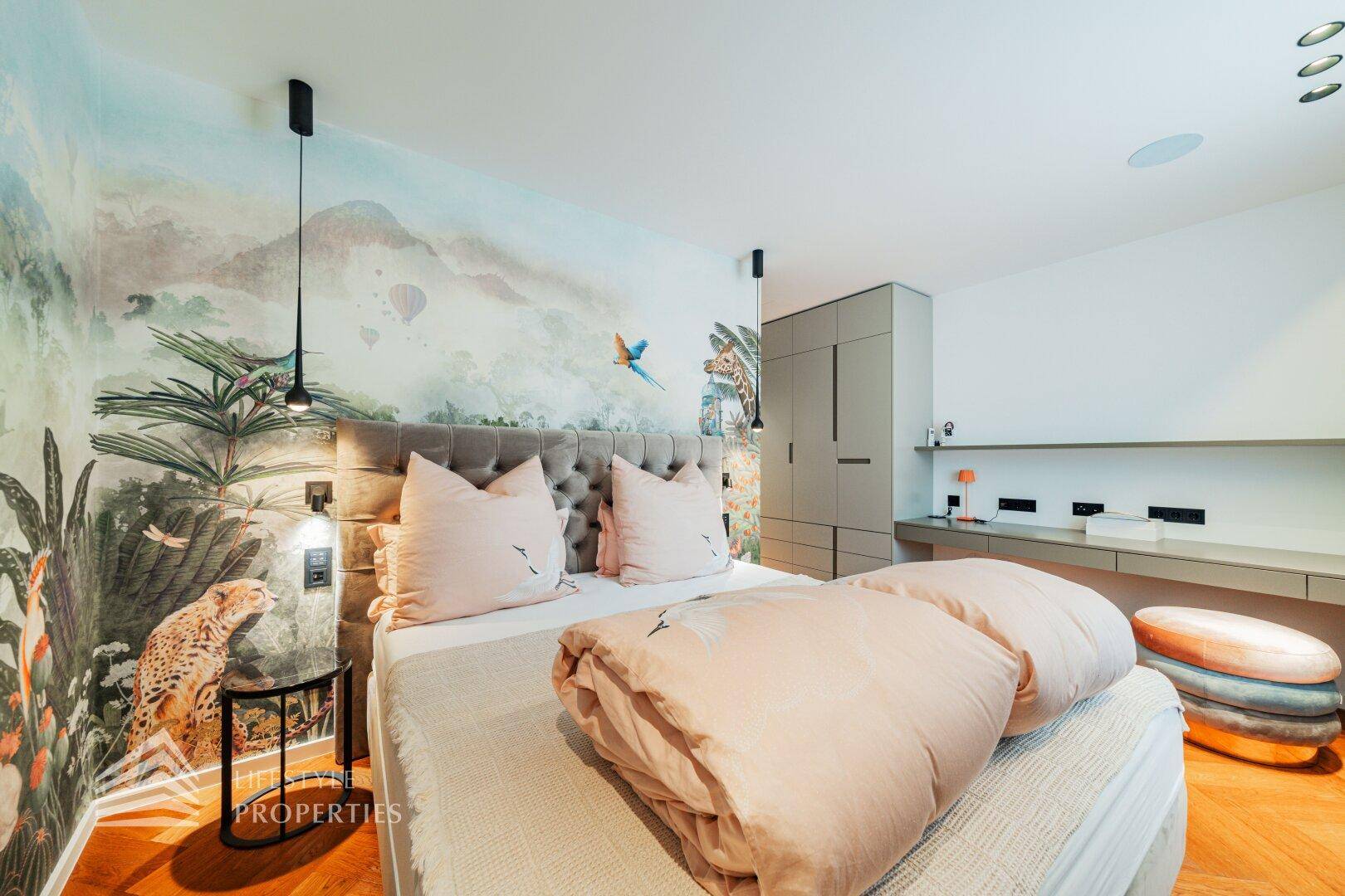 Kinderzimmer mit verspielter Tapete, großem Bett und integriertem Schreibtischbereich.