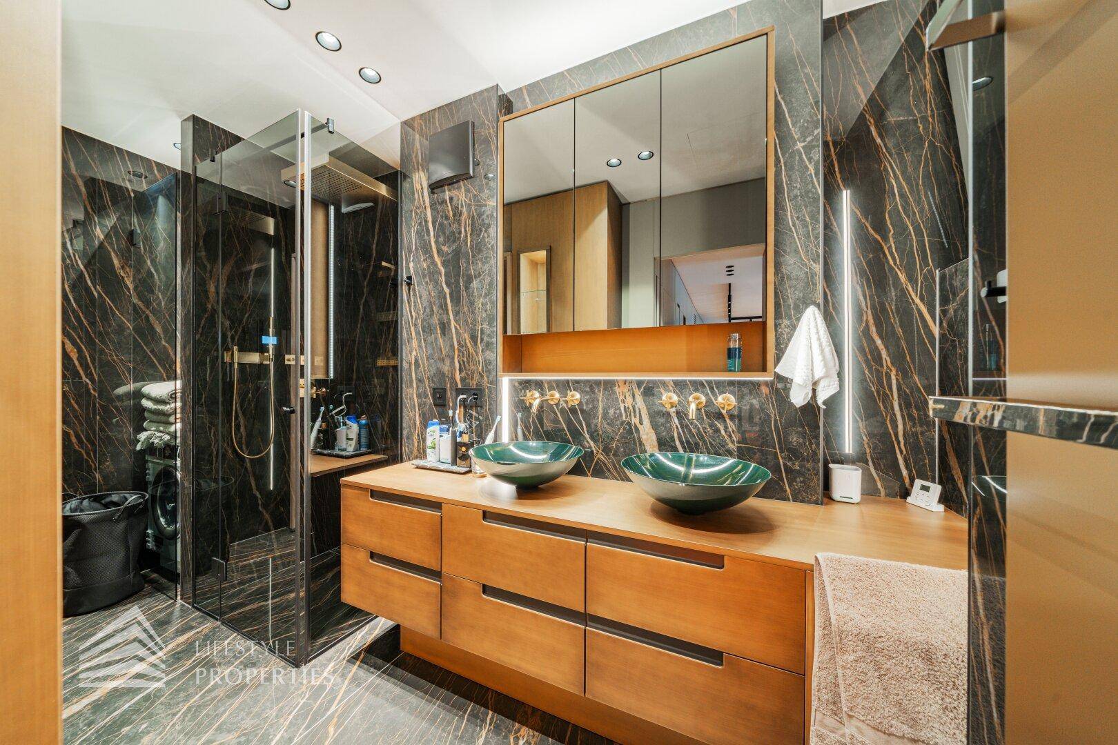Luxuriöses Badezimmer mit doppelten Waschbecken, großer Dusche und eleganten Marmoroberflächen.