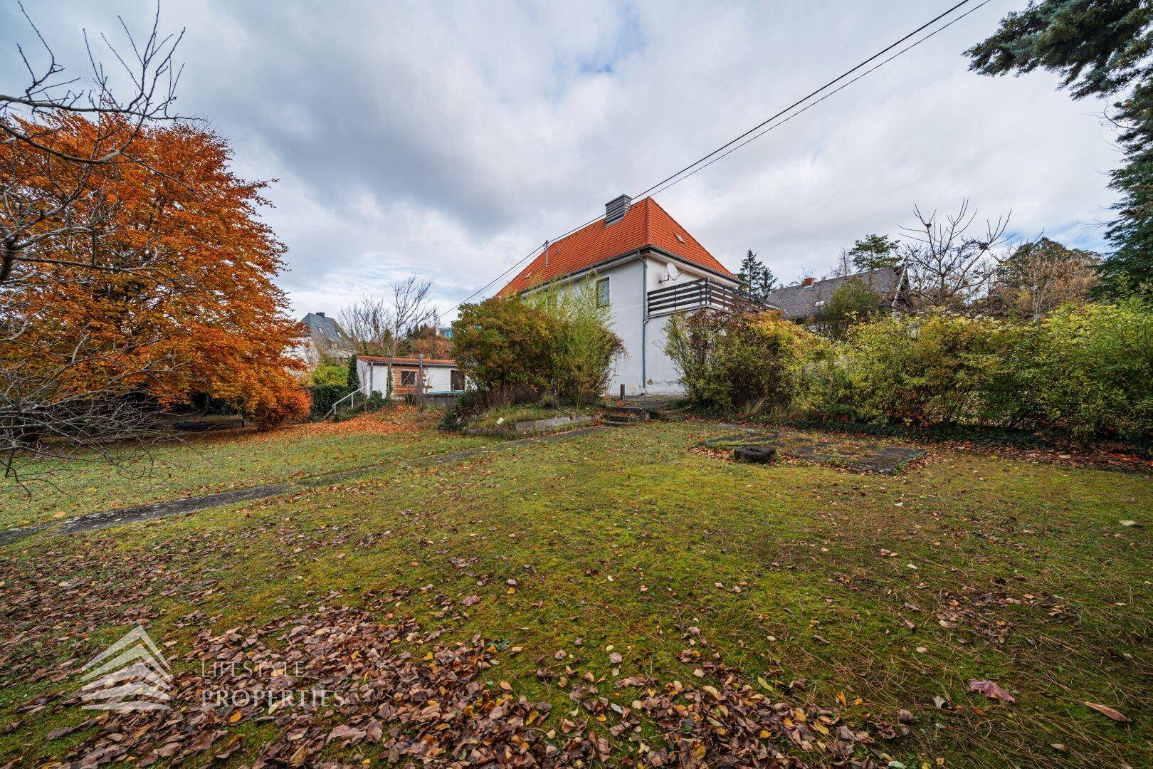 Hinterer Gartenbereich mit Rasenfläche und Blick auf die Rückseite des Hauses.