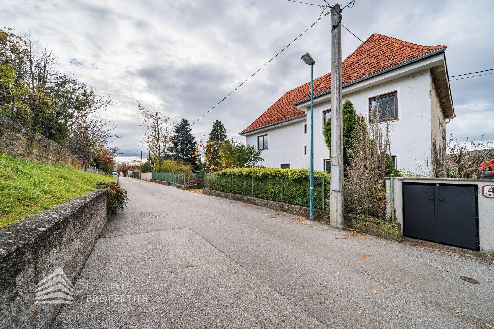 Ruhige Wohnstraße mit Laterne und Blick auf die Hauszufahrt.