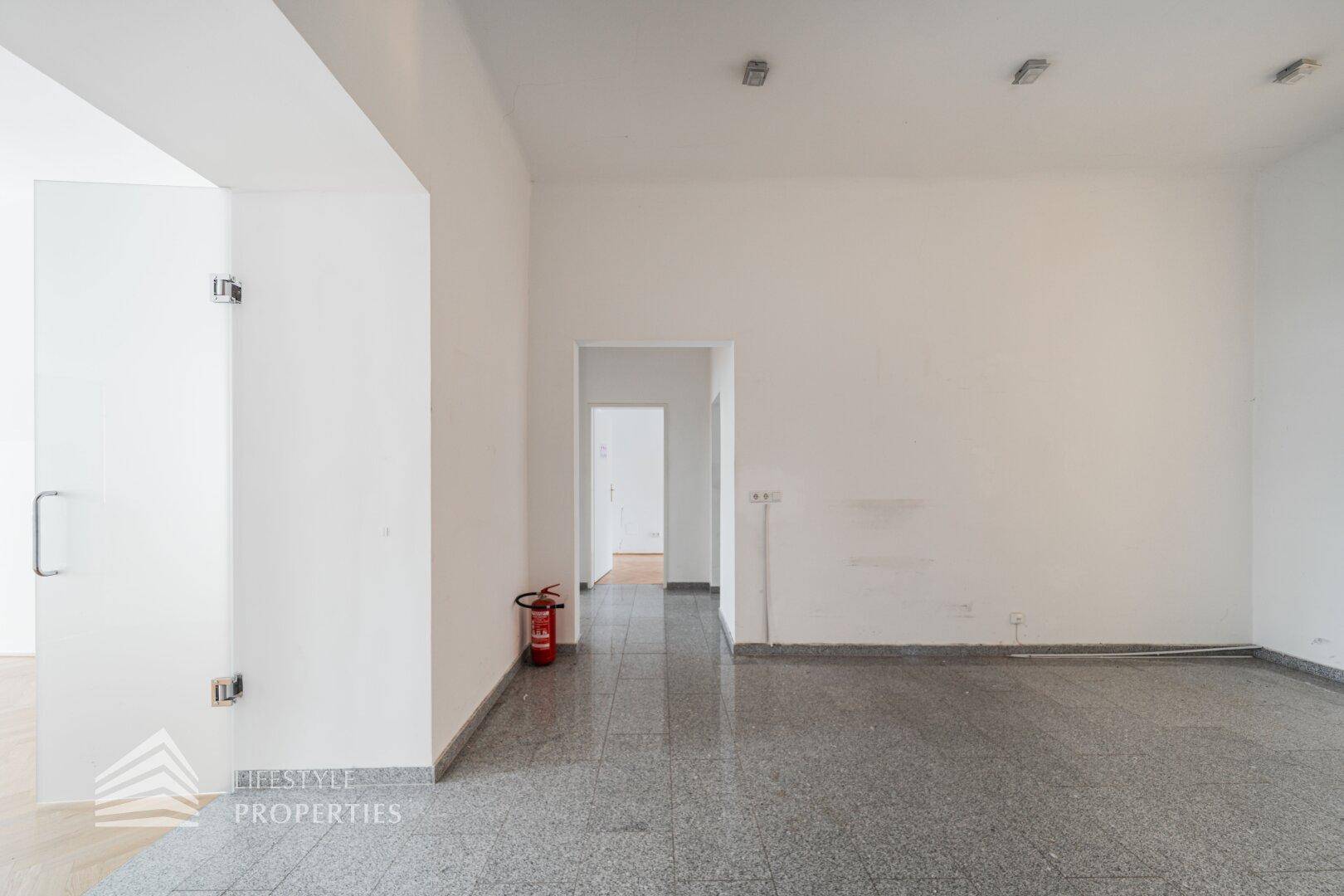 Heller, leerer Raum mit glänzendem Fliesenboden und einer modernen Glastür, ideal für Büronutzung.
