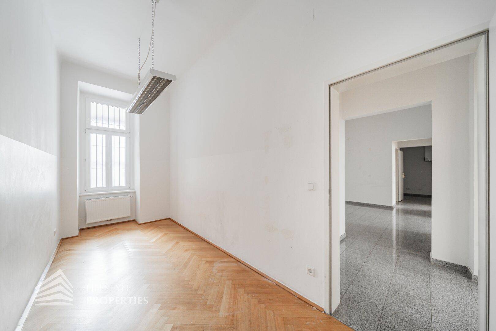 Heller Raum mit Fischgrätparkett und großem Fenster, bietet eine angenehme Arbeitsatmosphäre.