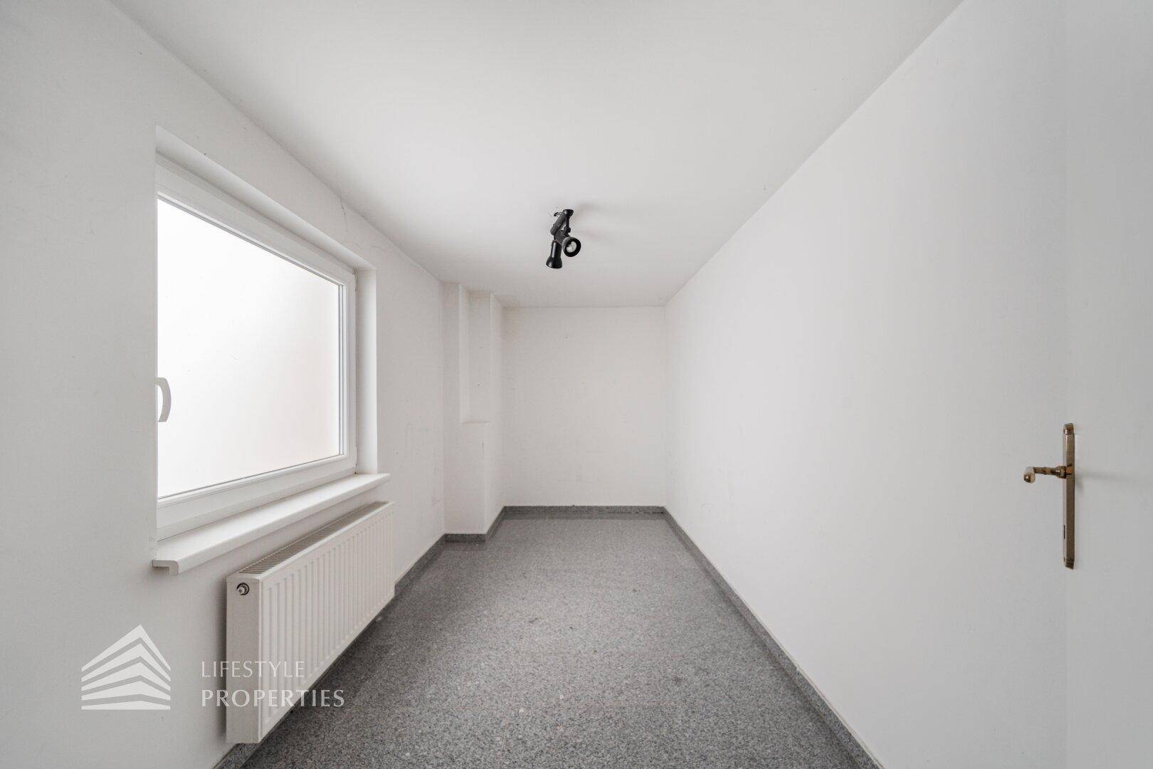 Schmaler Raum mit Fenster und Fliesenboden, geeignet als Abstellraum oder kleines Lager.