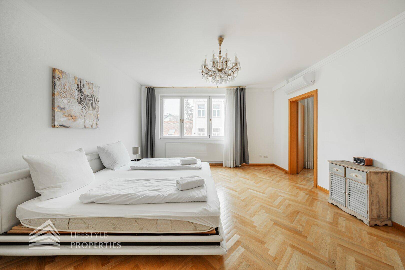 Helles Schlafzimmer mit Parkettboden, Doppelbett und Klimaanlage.