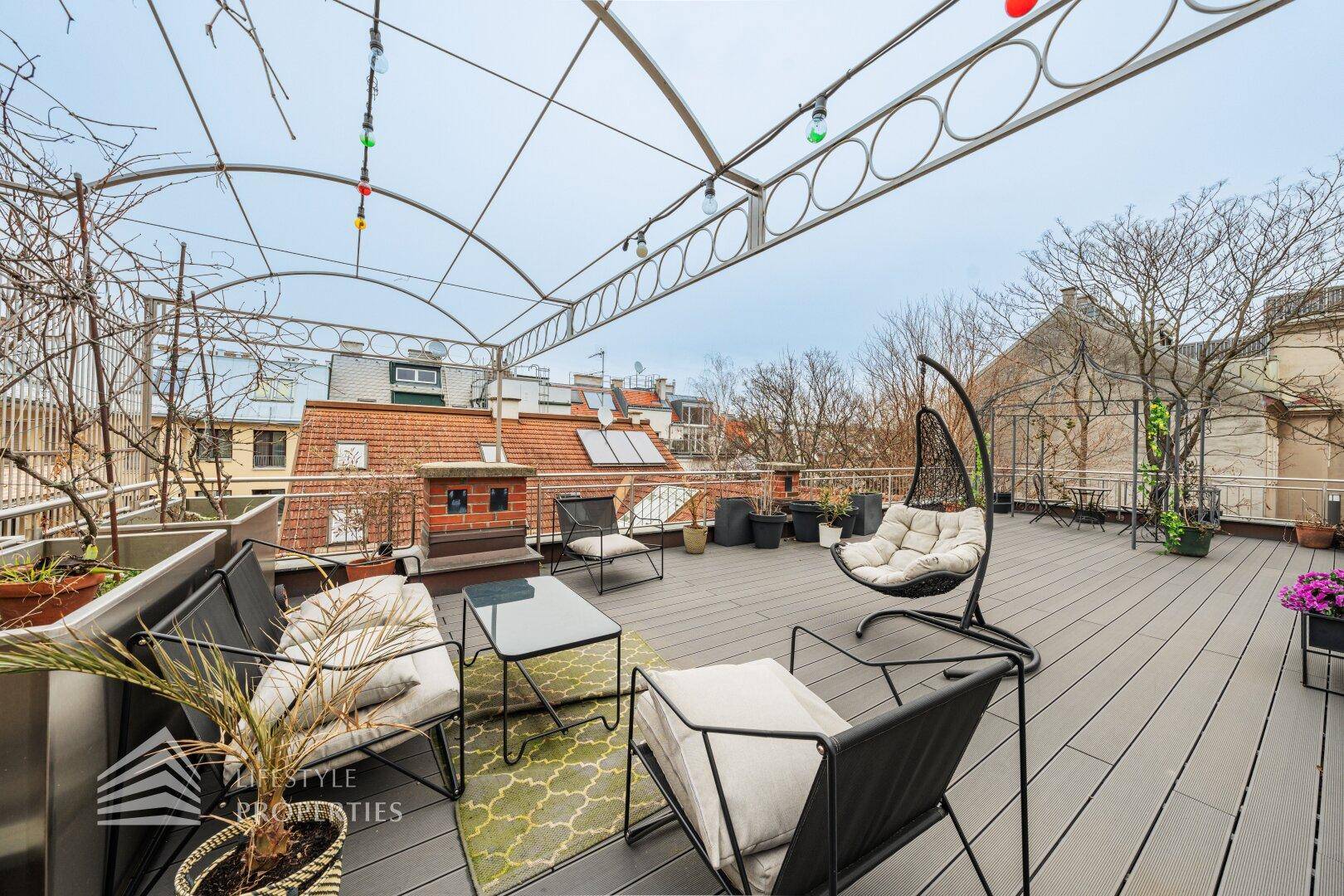 Große Dachterrasse mit Lounge-Möbeln, Pflanzen und Blick auf die Umgebung.