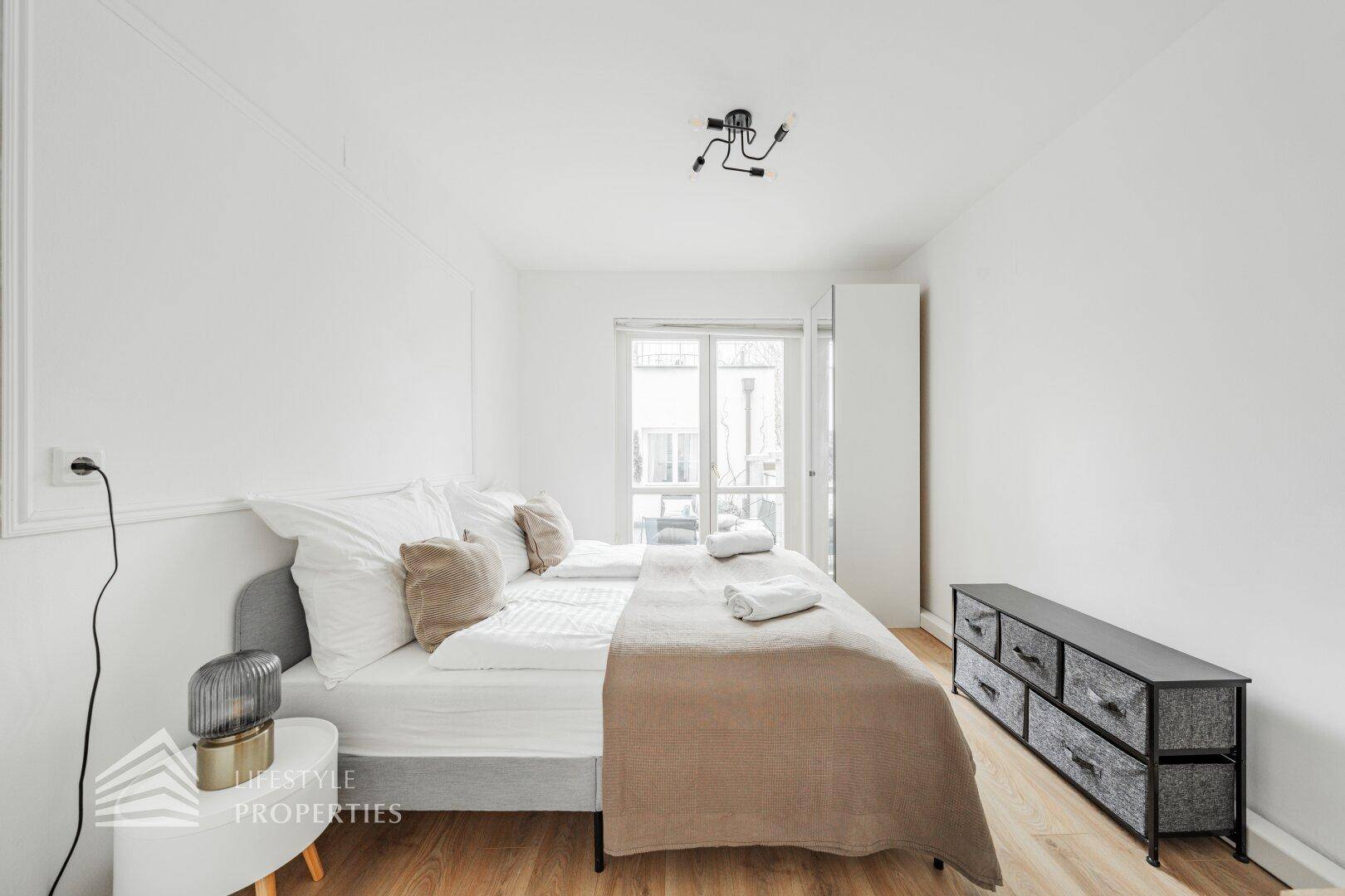 Schlafzimmer mit Holzboden, Doppelbett und Zugang zu einem Außenbereich.
