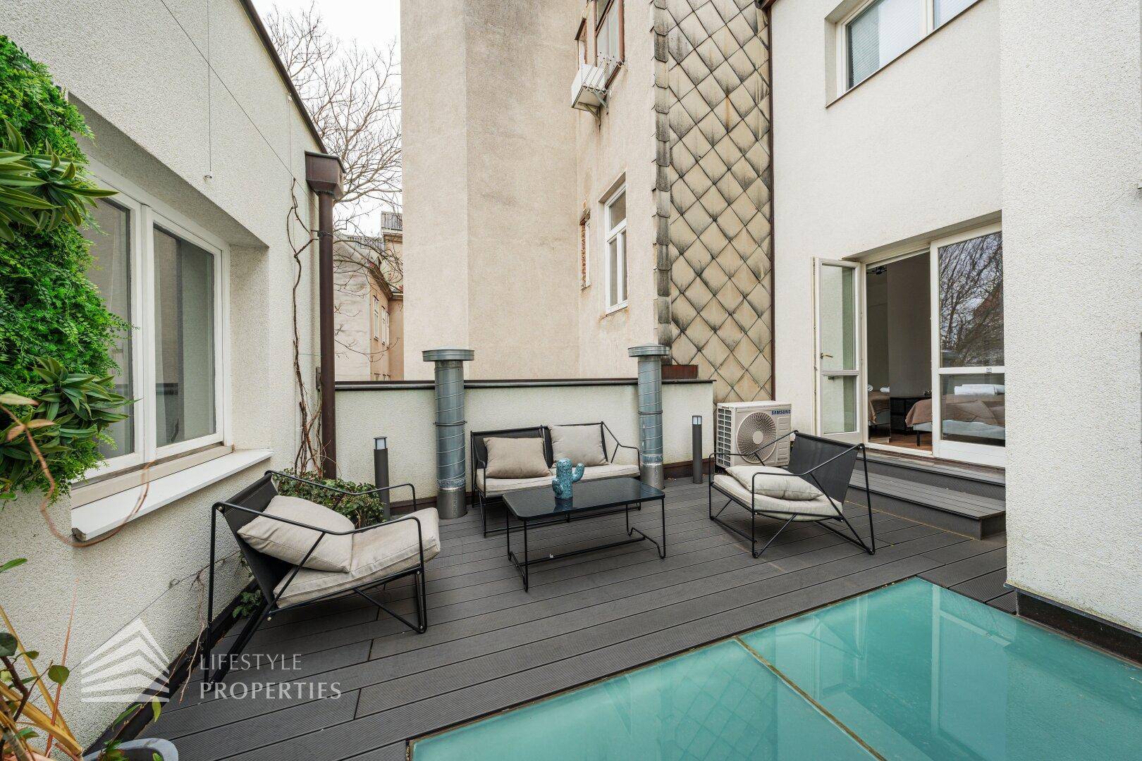 Kleine Terrasse mit Sitzgelegenheiten, Pflanzen und Zugang zu einem Innenraum.