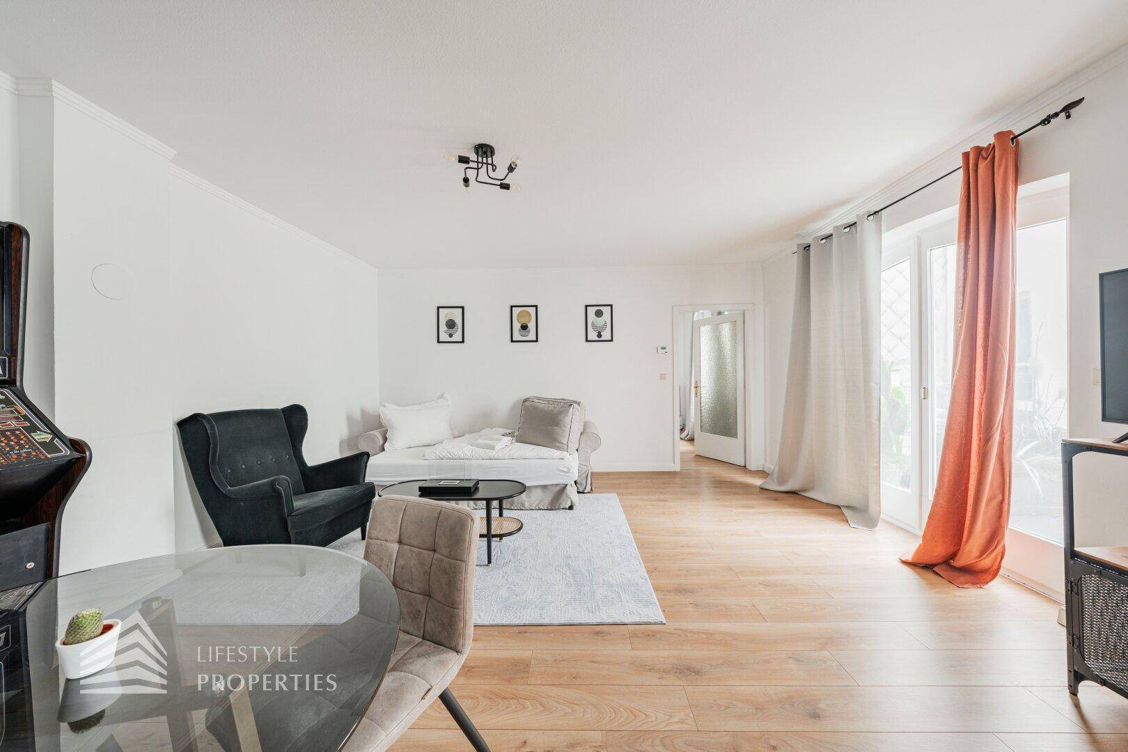 Heller Wohnbereich mit Holzboden, Sofa und Zugang zu einem Außenbereich.