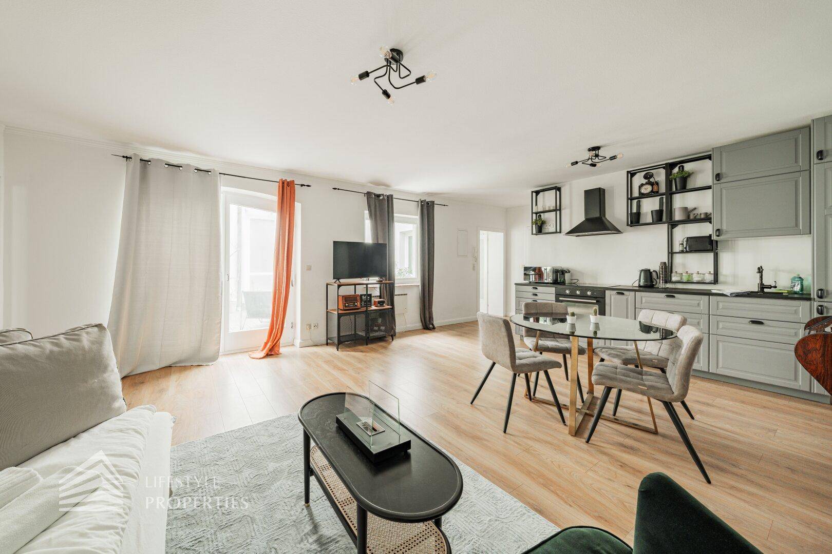 Heller Wohnbereich mit offener Küche, Esstisch und Zugang zum Balkon.