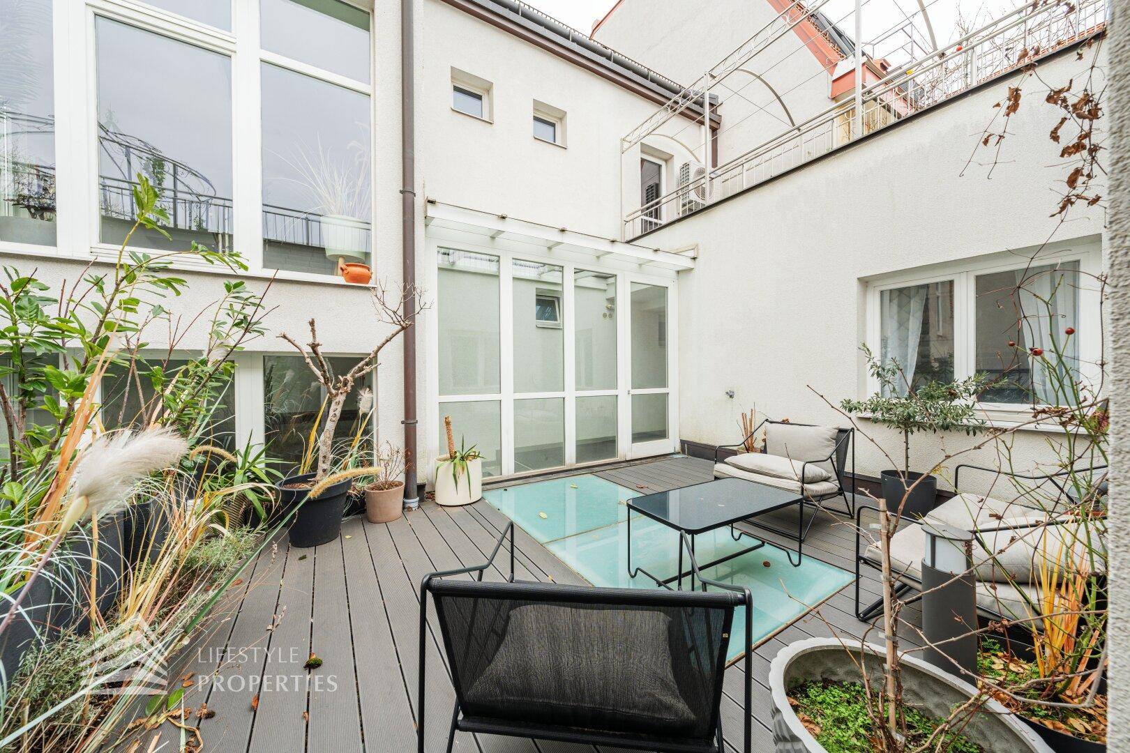 Gemütliche Terrasse mit Sitzgelegenheiten, Pflanzen und Glasboden-Elementen.