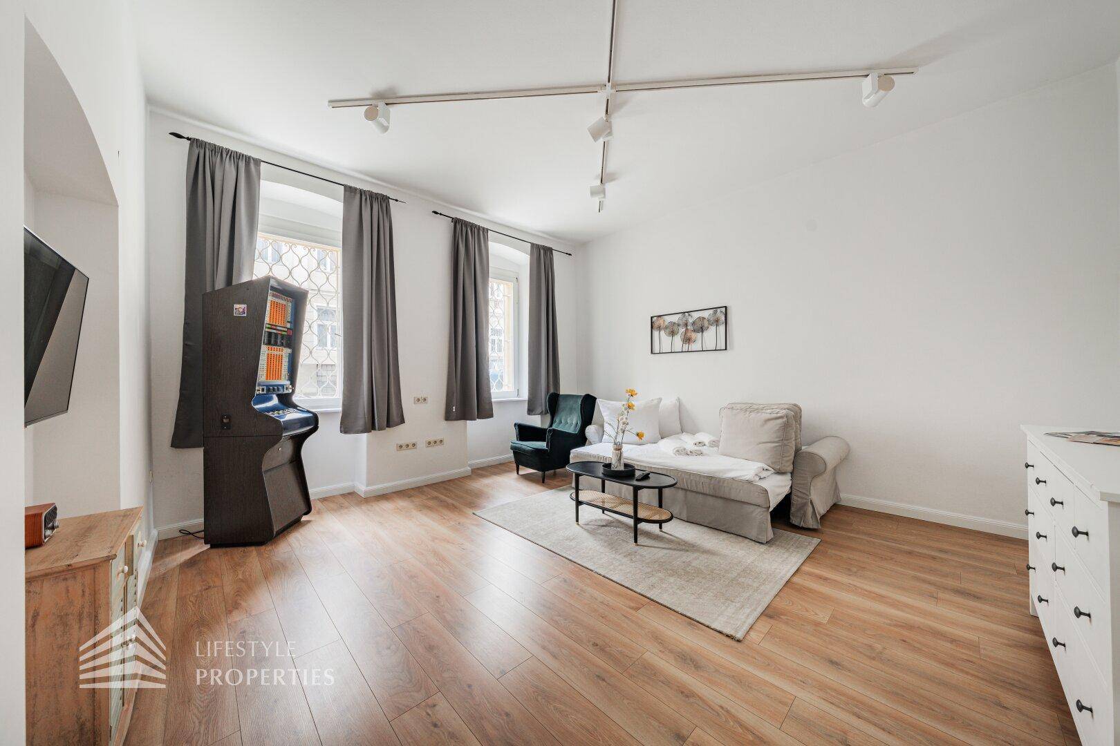 Helles Wohnzimmer mit Holzboden, Sofa und dekorativen Elementen.