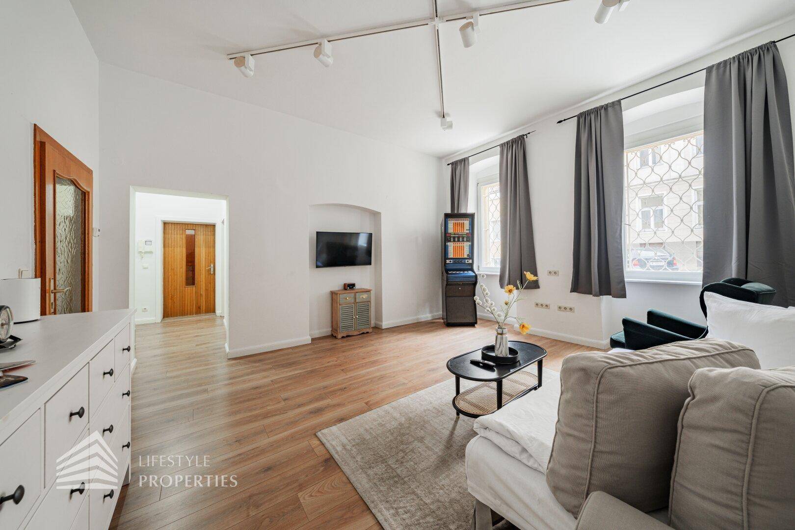Geräumiges Wohnzimmer mit Holzboden, Sofa und Blick auf die Straße.
