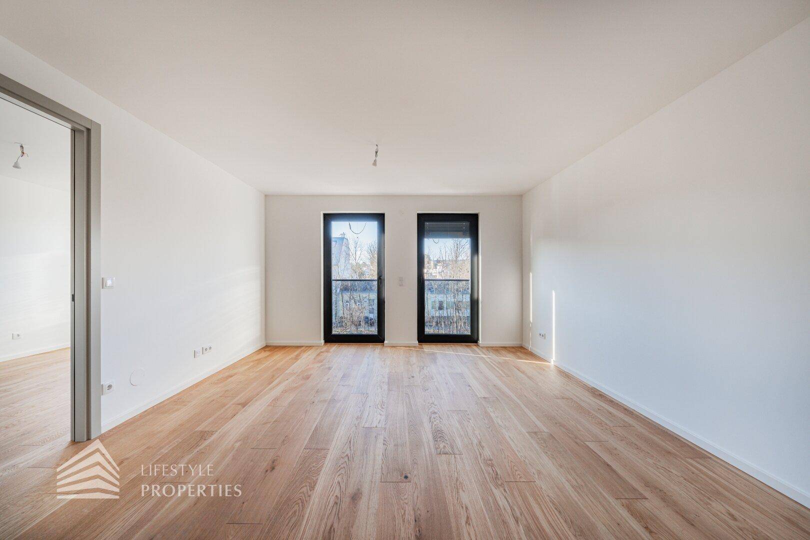 Geräumiges Zimmer mit elegantem Parkettboden und großen Fenstern, die für eine helle Atmosphäre sorgen.