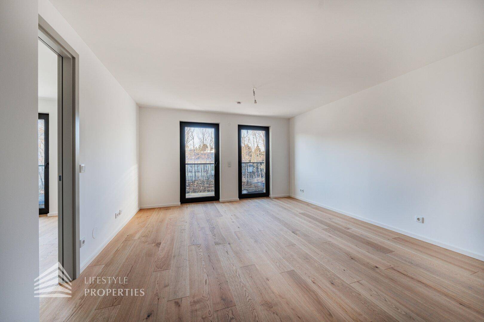 Geräumiges, helles Zimmer mit Parkettboden und Zugang zu französischen Balkonen.