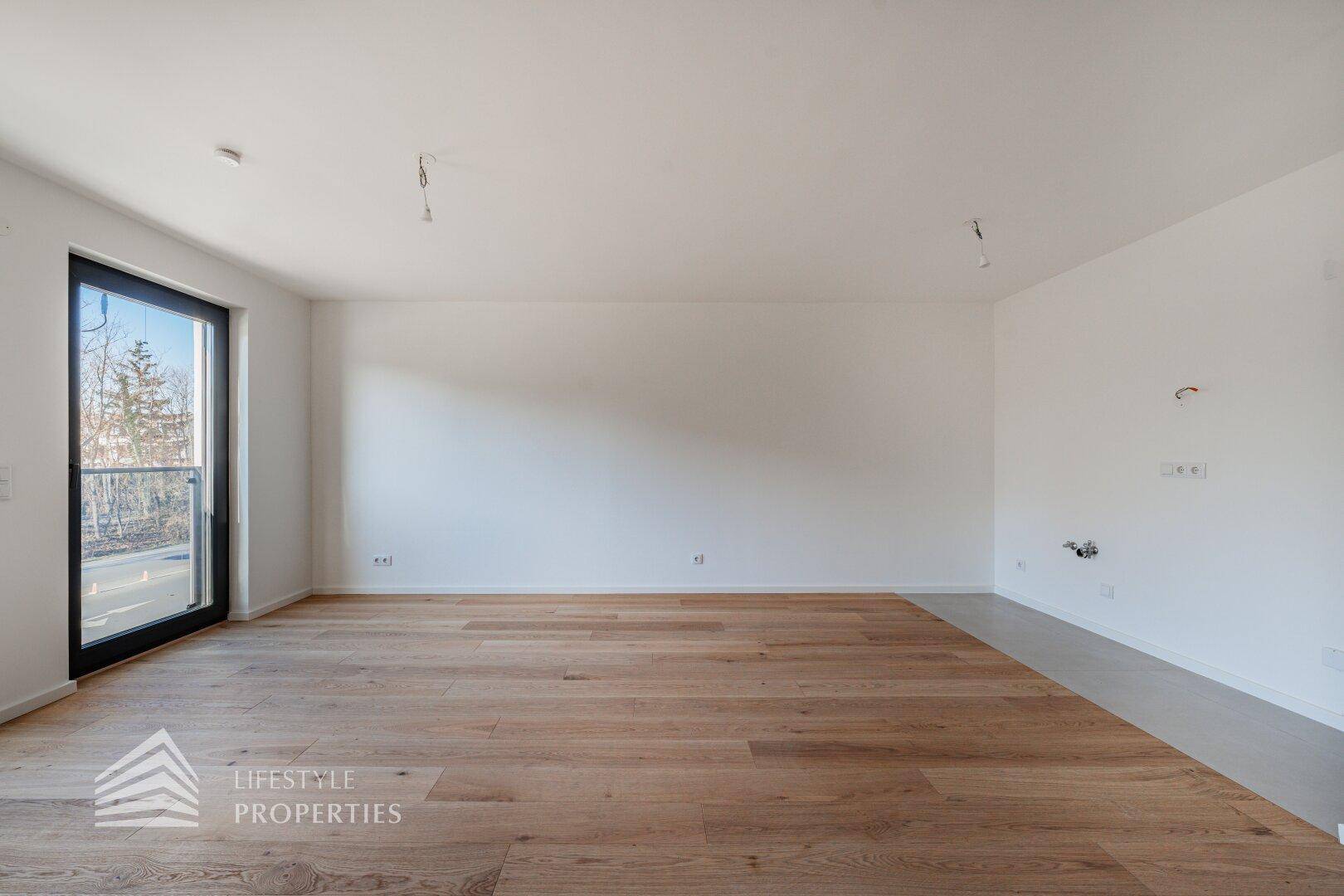 Geräumiges Zimmer mit Holzboden und Fenstertür, bereit für die individuelle Gestaltung.