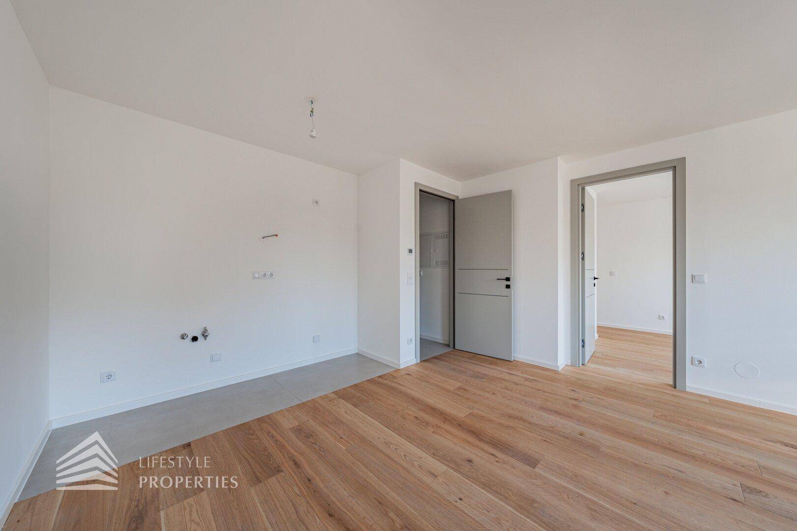 Leeres Zimmer mit Holzboden und einem Bereich für zukünftige Installationen.