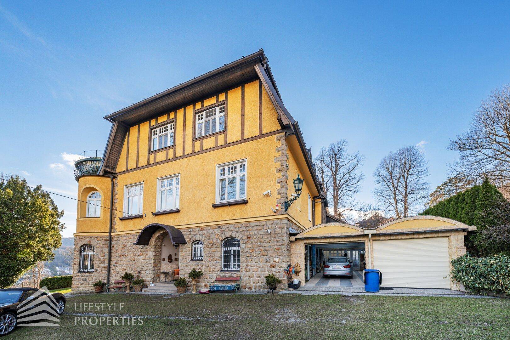 Vorderansicht der Villa mit Steinsockel, Eingangsbereich und integrierter Garage.