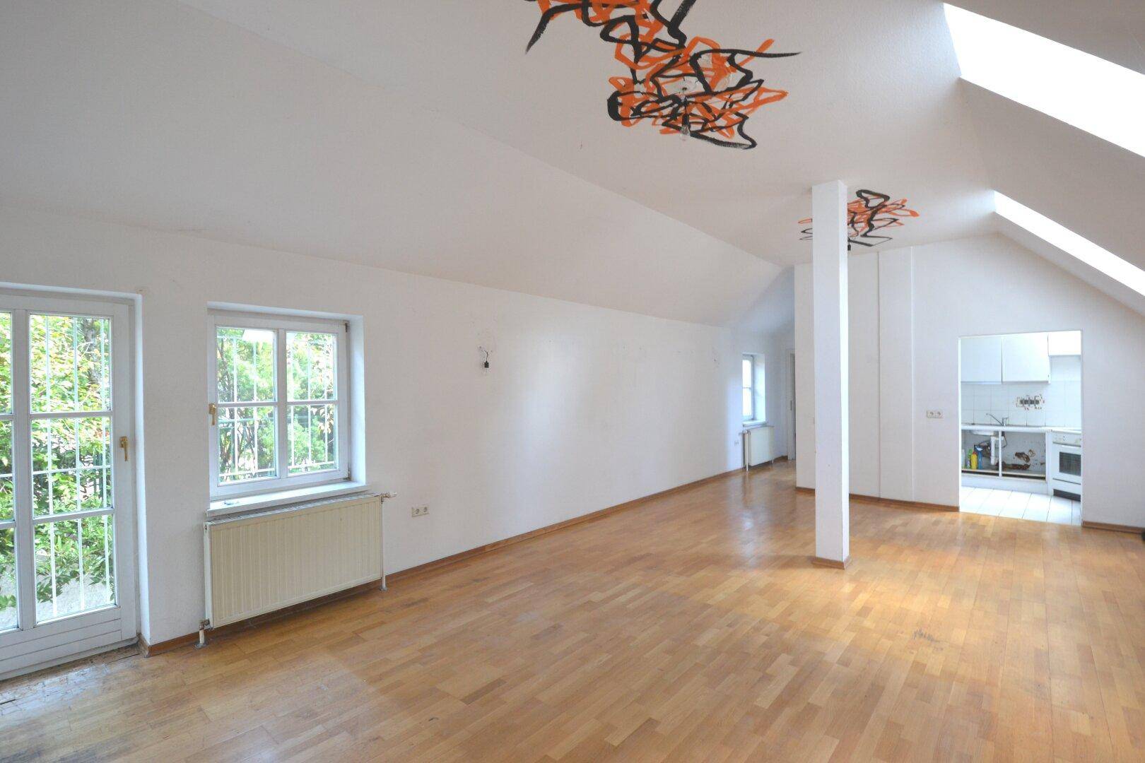 Geräumiges Wohnzimmer mit Holzboden, Heizkörpern und Zugang zu einem Balkon durch große Türen.