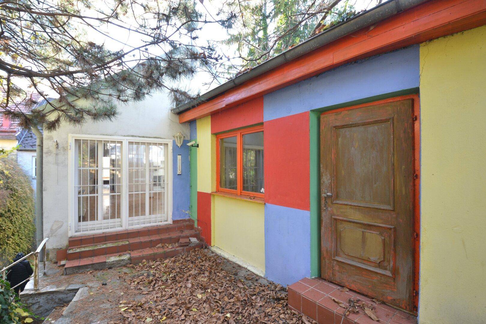 Buntes Haus mit verschiedenen Farbfeldern an der Fassade und einer alten Holztür.
