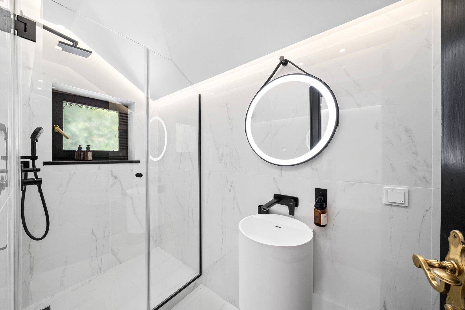 Modernes Badezimmer mit schwarzem Design, runden Spiegeln und begehbarer Dusche.