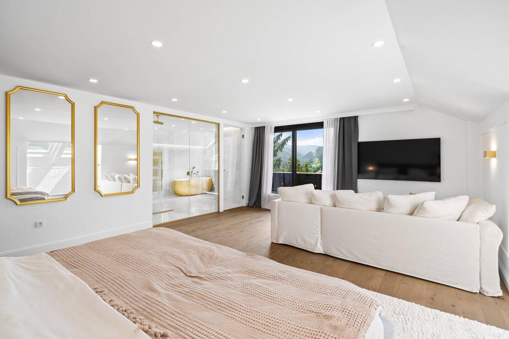 Luxuriöses Schlafzimmer mit Holzboden, großem Bett und integriertem Badezimmerbereich.