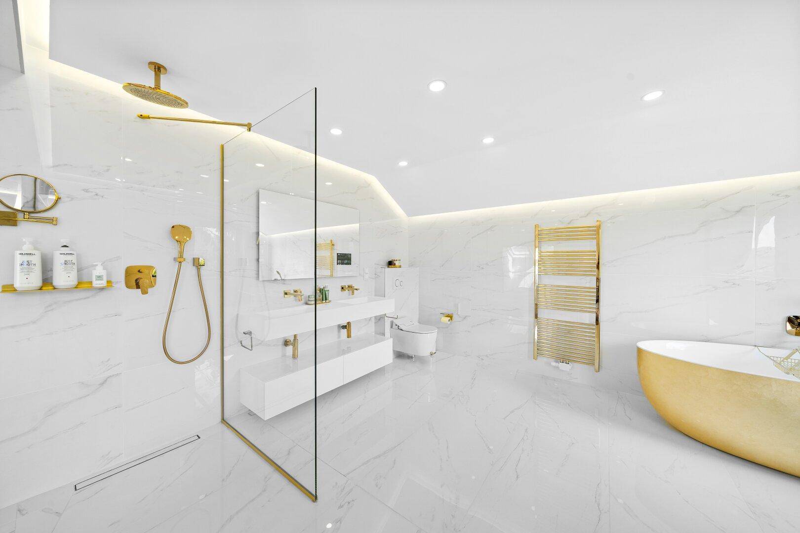 Luxuriöses Badezimmer mit Marmorfliesen, goldfarbenen Armaturen und freistehender Badewanne.
