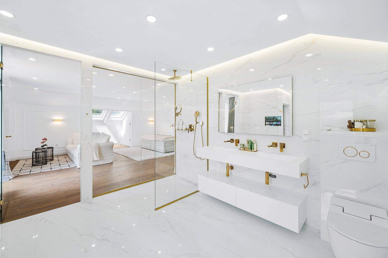 Modernes Badezimmer mit Marmorfliesen, Glasdusche und Blick auf das Schlafzimmer.