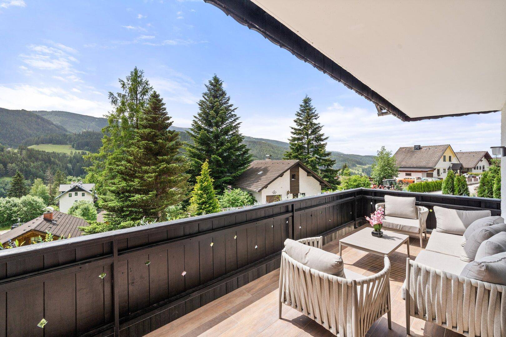Möblierter Balkon mit bequemen Sitzgelegenheiten und Panoramablick auf die Berge.