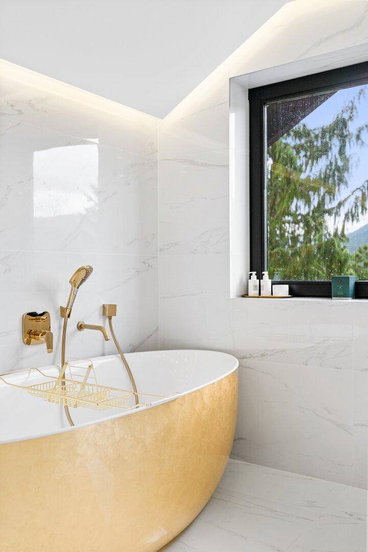 Detailaufnahme der goldenen Badewanne mit Blick auf die grüne Landschaft.