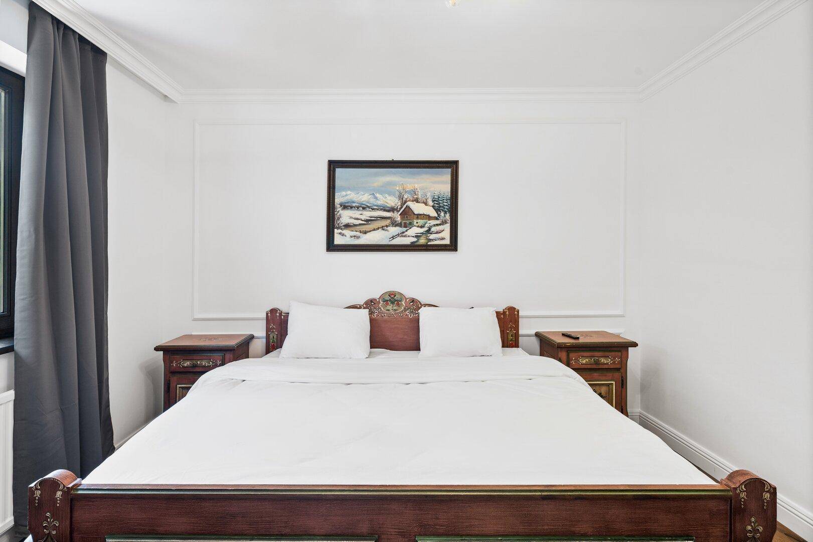 Gemütliches Schlafzimmer mit traditionellem Holzbett und einem Gemälde an der Wand.