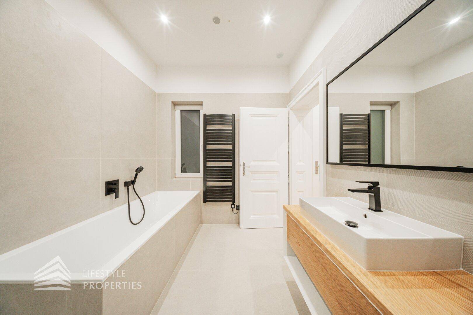 Modernes Badezimmer mit Badewanne, Einzelwaschbecken und beheiztem Handtuchhalter.