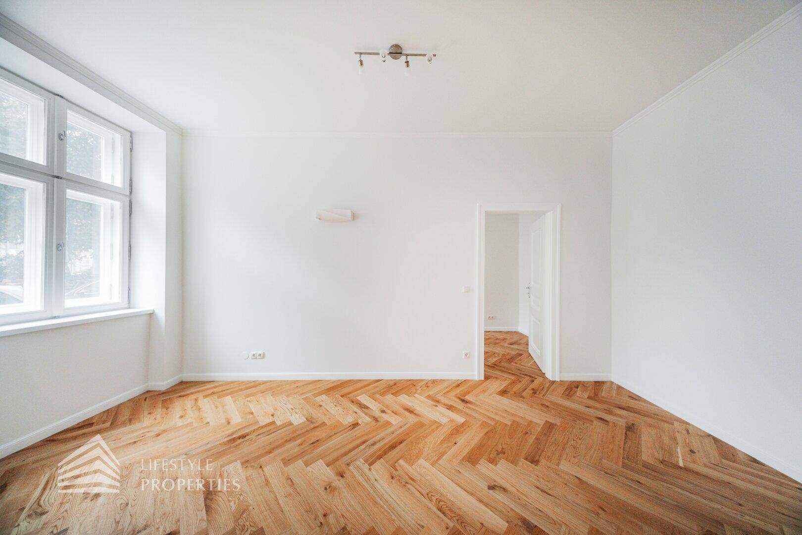 Geräumiges, helles Zimmer mit klassischem Fischgrätparkett und Blick ins Grüne.