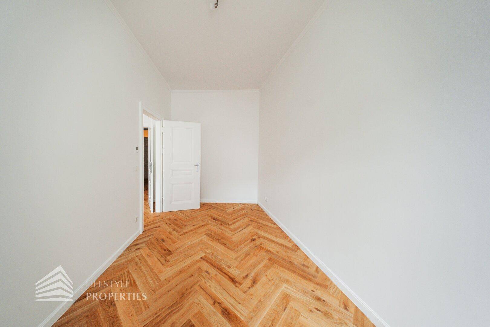 Schmaler, heller Raum mit Fischgrätparkett, ideal als Arbeitszimmer oder Abstellraum.