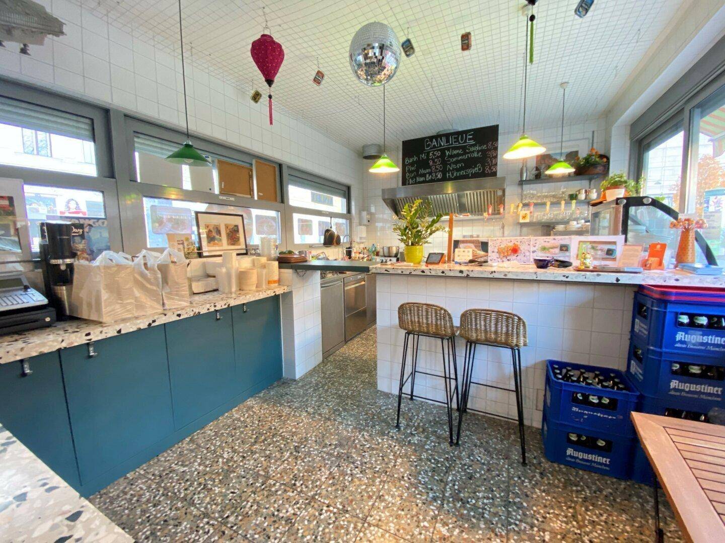 Heller Gastronomiebereich mit Theke, Barhockern und großen Fenstern, ideal für einen Imbiss oder Café.