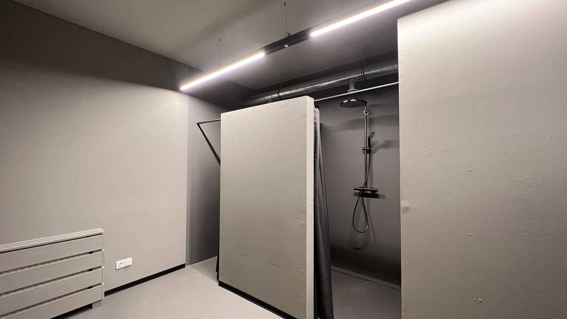 Moderner Duschbereich mit minimalistischem Design, grauen Wänden und einer Regendusche.