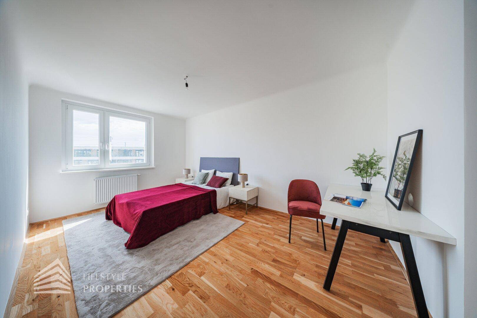 Großes Schlafzimmer mit Doppelbett, Holzboden und Schreibtischbereich.
