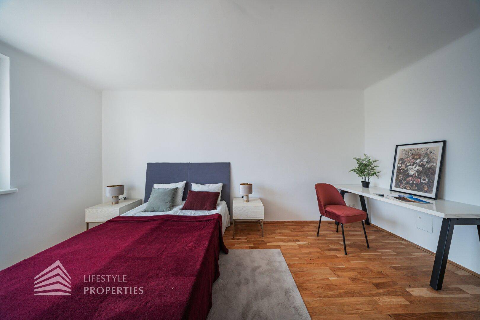 Geräumiges Schlafzimmer mit Doppelbett, Holzboden und Arbeitsbereich.