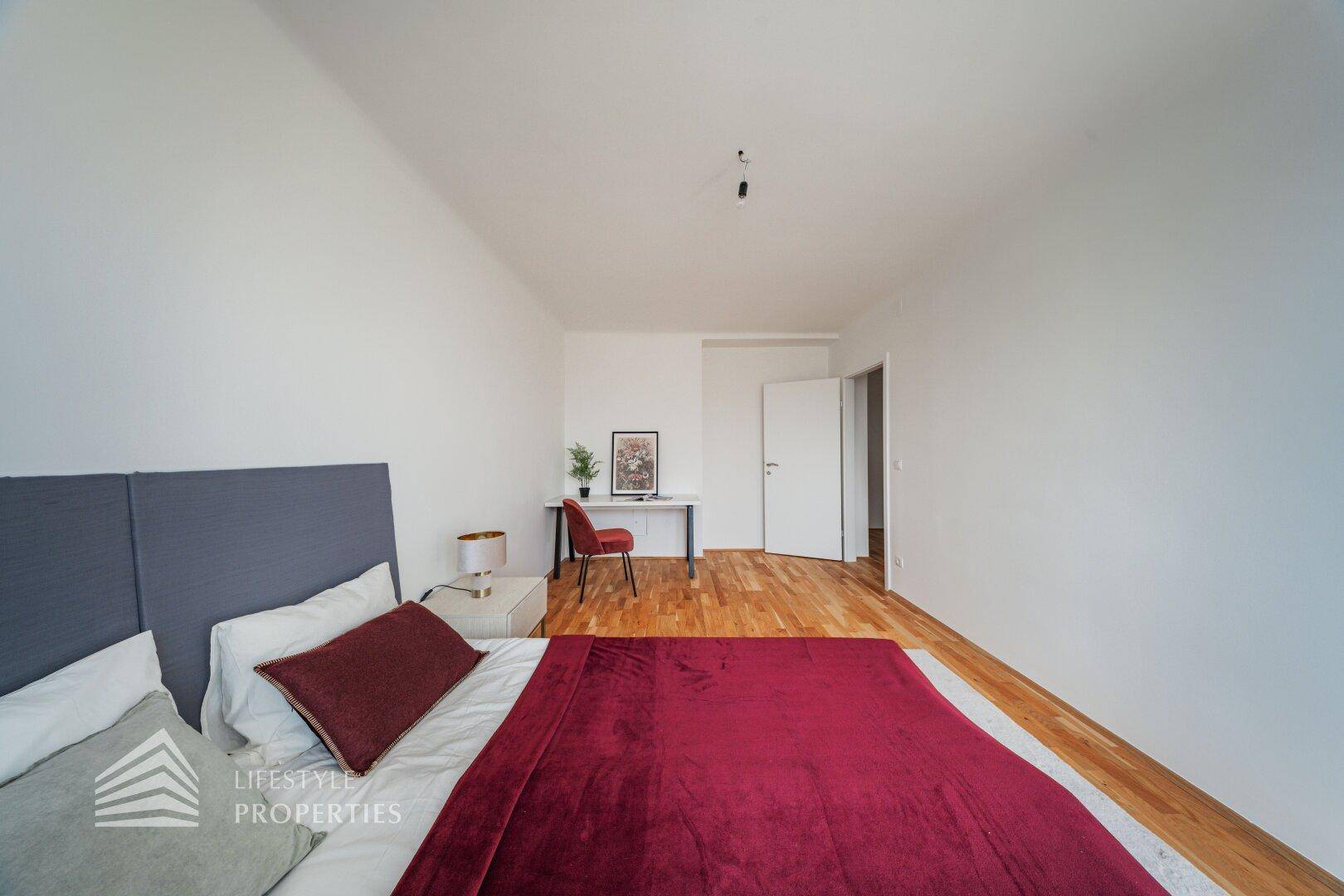 Schlafzimmer mit Holzboden und Zugang zu einem weiteren Raum.