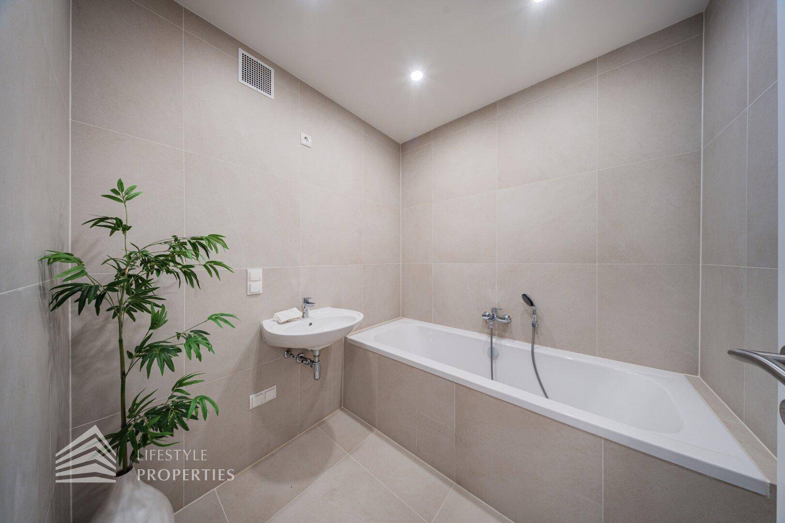 Modernes Badezimmer mit Badewanne, Waschbecken und Fliesenboden.
