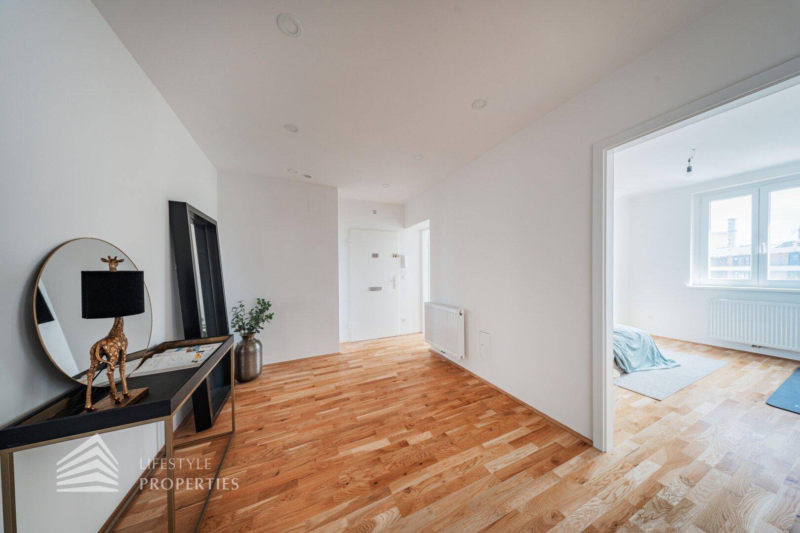 Geräumiger Flur mit Holzboden und moderner Dekoration, führt zu weiteren Räumen.