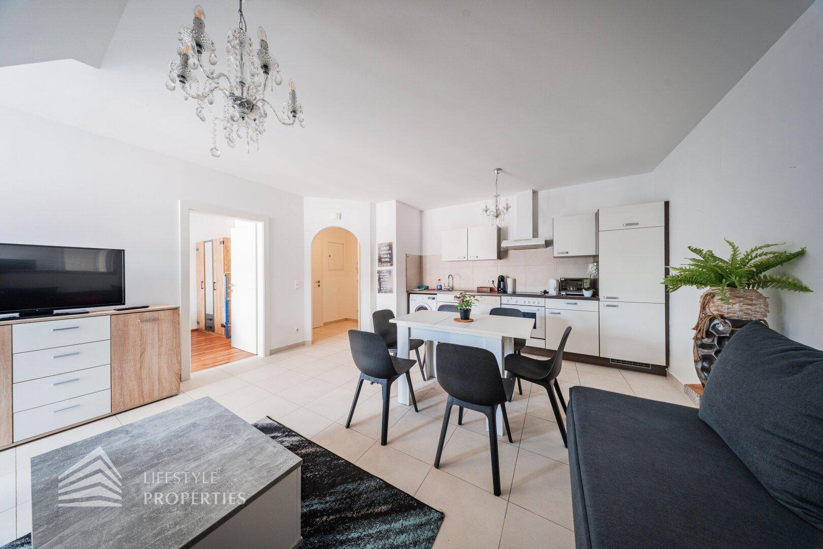 Geräumiger Wohnbereich mit offener Küche, Esstisch und bequemer Couch, ideal für geselliges Beisammensein.