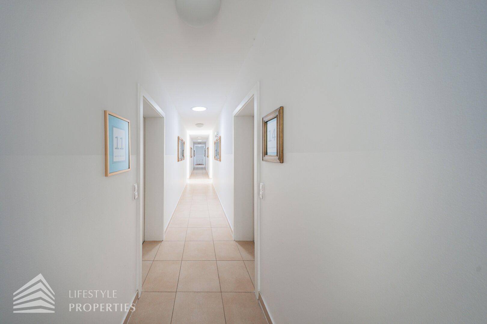 Geräumiger Flur mit Fliesenboden und Türen zu den Apartments, gut beleuchtet und gepflegt.