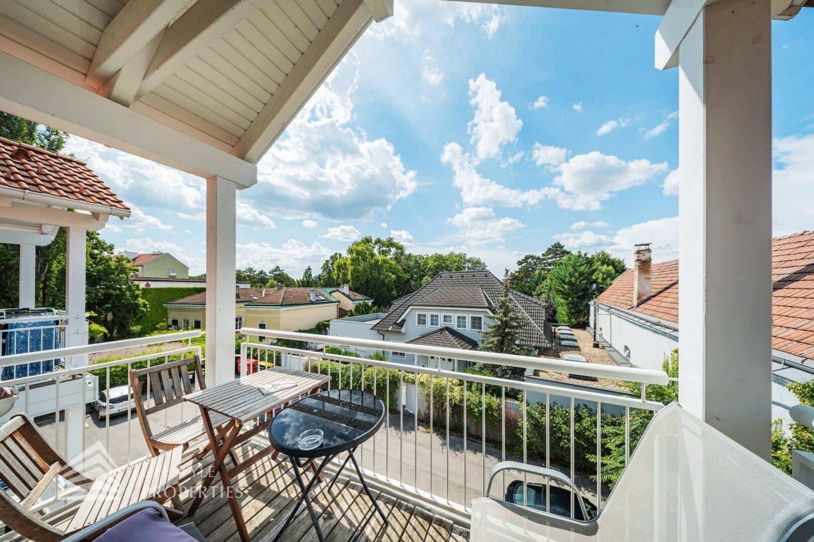 Überdachter Balkon mit Holzboden und Sitzgelegenheiten, bietet einen schönen Blick ins Grüne.